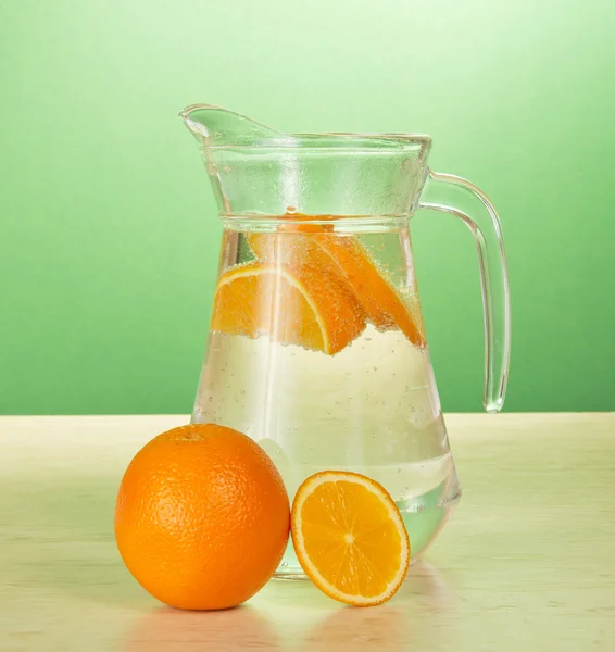 Krug mit Kaltgetränk und Orangen auf dem Tisch — Stockfoto