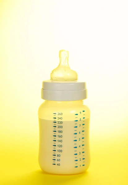 Pequeño biberón para la alimentación del niño, en el amarillo —  Fotos de Stock