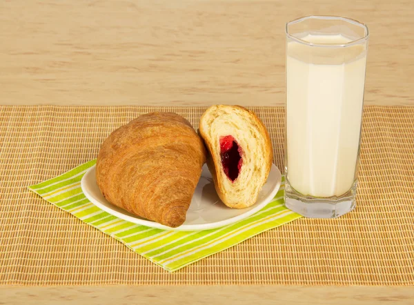 Croissants, melk, gestreepte servet op een beige bamboe doek — Stockfoto