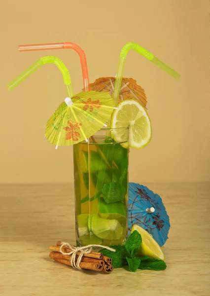 A bebida com palhas decora-se com guarda-chuvas e paus de canela amarrados por uma corda, no bege — Fotografia de Stock