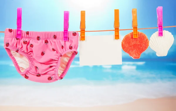 Panties, lege kaart en mantel aan een touw, tegen de zee — Stockfoto