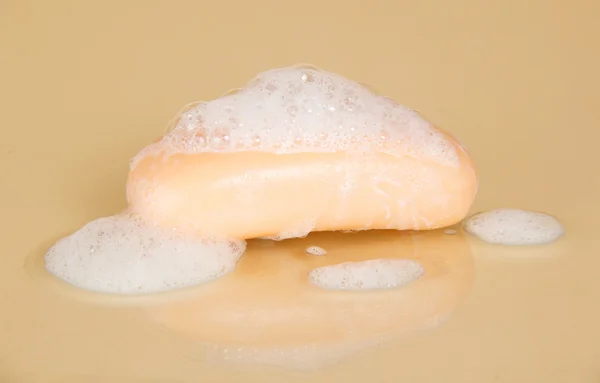 Stuk zeep met zeepsop op een beige achtergrond — Stockfoto