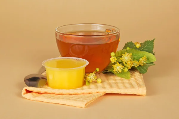 Cup of tea a honey a branch of a linden and a napkin on a beige background — Stock Photo, Image