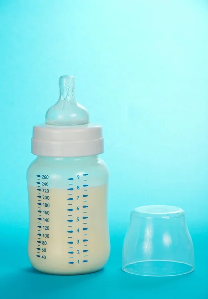 Kleine fles met melk en een cover, op een blauwe achtergrond — Stockfoto