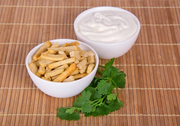 Bowl with sour cream, a bowl with toasts and parsley, on a bamboo cloth — Stock Photo, Image