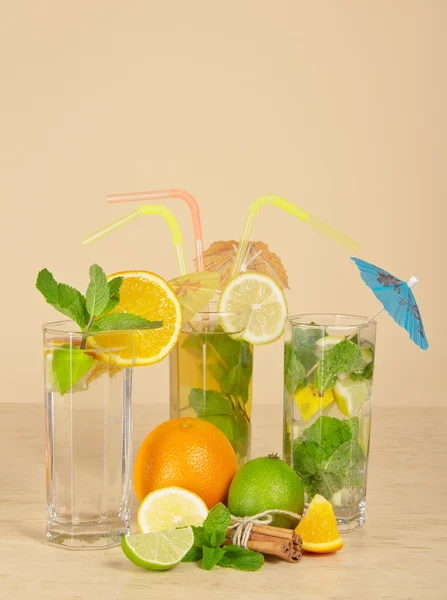 Tea with a lemon, orange drink and cocktail, cinnamon sticks tied up by a rope, on the beige — Stock Photo, Image