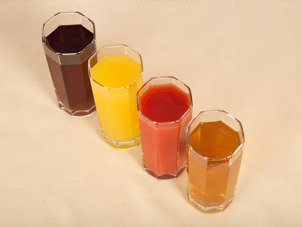 Glasögon med olika saft på en beige tyg — Stockfoto