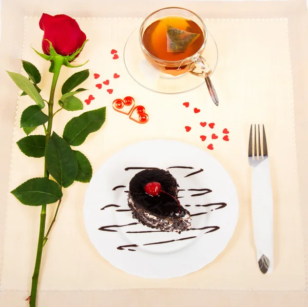 Pastel de chocolate, té caliente y rosa roja en un paño decorado con corazones en el día de San Valentín —  Fotos de Stock