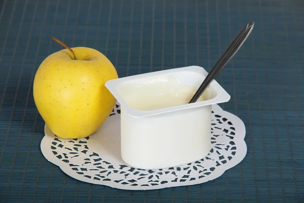 Doos met yoghurt, apple en een servet op blauwe achtergrond — Stockfoto