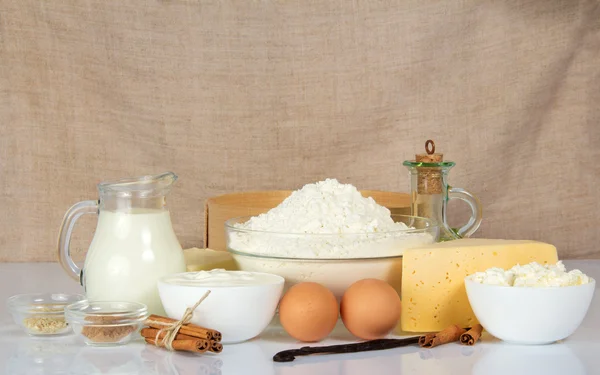 Dairy products, flour, eggs, cheese, spices against a canvas — Stock Photo, Image