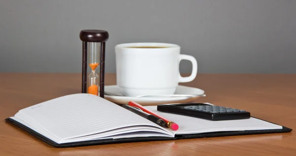 Otevřete poznámkový blok, pero, tužka, kalkulačka, hodiny a šálek kávy — Stock fotografie