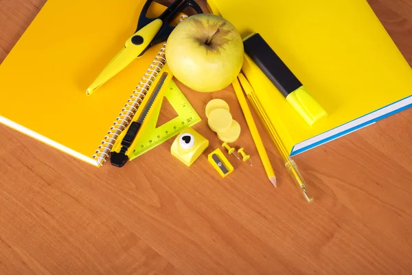 O livro, o bloco de notas, grupo de instrumentos de escritório e maçã em uma mesa — Fotografia de Stock