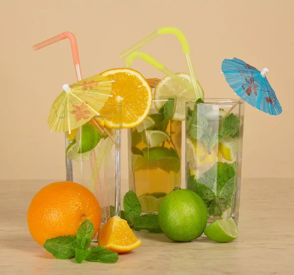 Chá com limão, bebida de laranja e coquetel em uma mesa bege — Fotografia de Stock