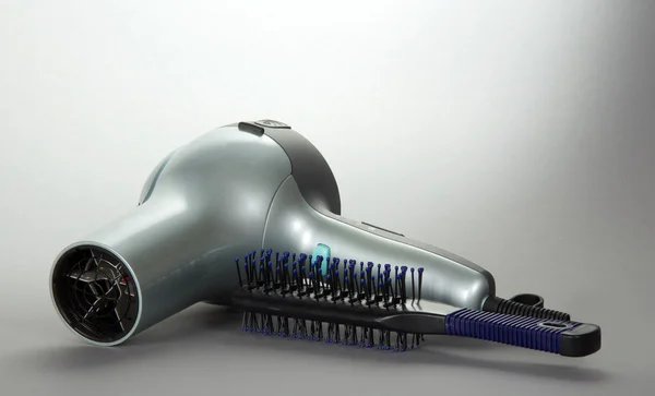 Saç kurutma makinesi saç ve gri arka plan üzerinde bir saç fırçası — Stok fotoğraf
