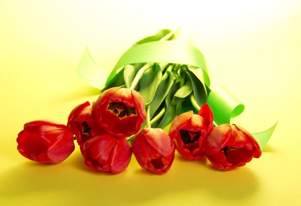 Il bouquet di tulipani decorato con un nastro e un biglietto vuoto per il testo su sfondo giallo — Foto Stock