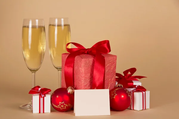 Regalos y juguetes de Navidad, champán, una tarjeta vacía sobre fondo beige —  Fotos de Stock