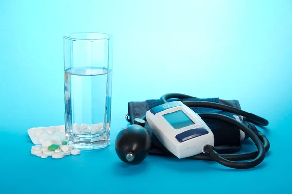 Il dispositivo digitale per misurazione di pressione arteriosa e una targa su uno sfondo azzurro — Foto Stock