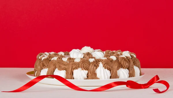 Torta di biscotti su un panno bianco e un nastro, su uno sfondo rosso — Foto Stock