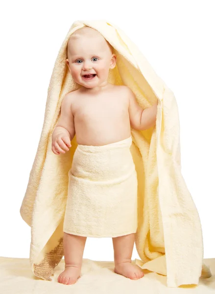 Веселый ребенок стоит, завернутый в желтое полотенце, изолированное на белом — стоковое фото