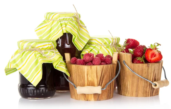 Jars of jam are closed by a paper napkin and tied by a twine, a bucket of strawberry and raspberry — Stock Photo, Image