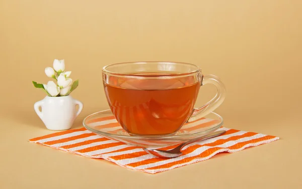 Taza de té, jazmín en un jarrón pequeño, una servilleta rayada, en el beige —  Fotos de Stock