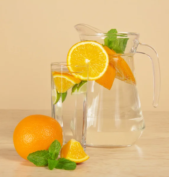 Kannu, lasi juoman kanssa, kypsä appelsiini ja minttu — kuvapankkivalokuva
