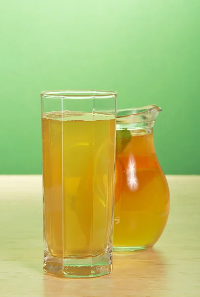 Dzbanek z zielonej herbaty i dzban z pomarańczowy napój na stole — Zdjęcie stockowe