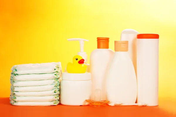 Baby cosmetics and diapers, on an orange background — Stock Photo, Image