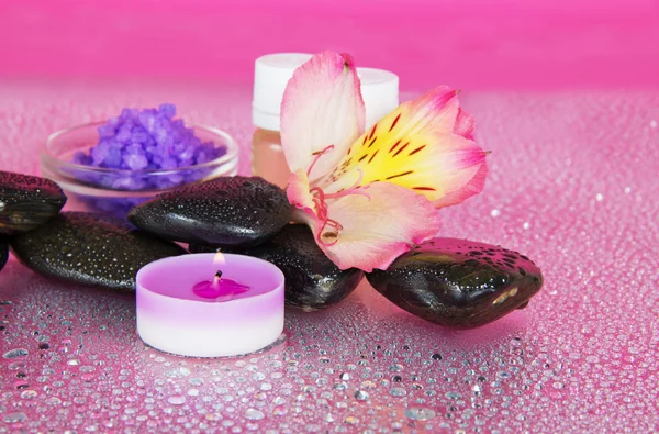 Vela e óleo de aroma, sal, pedras e uma flor — Fotografia de Stock