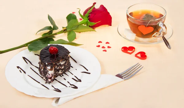 Шоколадный торт, горячий чай и красная роза на ткани, украшенной сердцами в День Святого Валентина — стоковое фото