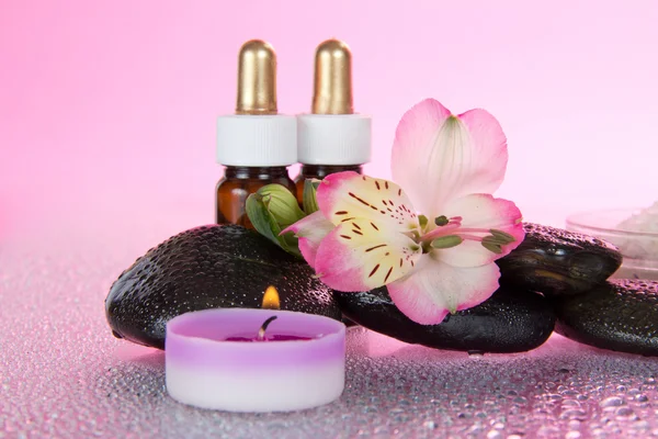 Candles and aroma oil, salt, stones and a flower, on a pink background — Stock Photo, Image