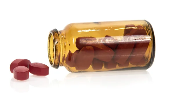 Comprimidos rojos, frasco aislado en blanco — Foto de Stock