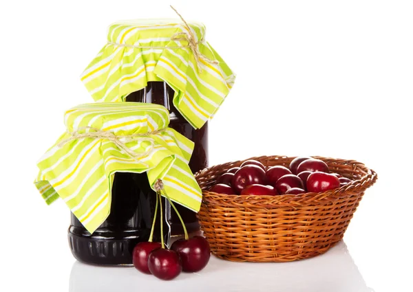 Jars of jam, a wicker basket with the sweet cherries — Stock Photo, Image