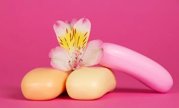 Jogo de sabão de toucador e a flor de um alstroemeria em um contexto rosa — Fotografia de Stock