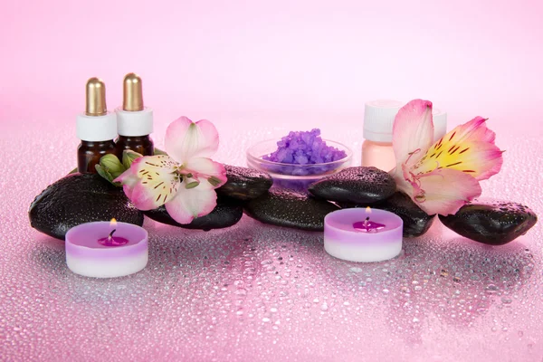 Sada vonných olejů, sůl, svíčky, kameny, gumičkou, na růžovém pozadí — Stock fotografie