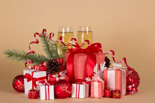 Geschenkboxen, Weihnachtsspielzeug, Tannenzapfen, Serpentinen und Weingläser mit Champagner auf beigem Hintergrund — Stockfoto