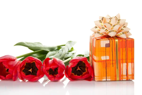 Bright gift box with a bow and the tulips — Stock Photo, Image