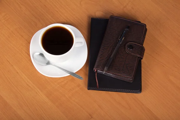 Bloc-notes, organisateur, la poignée, une tasse de café, soucoupe et cuillère sur une table — Photo