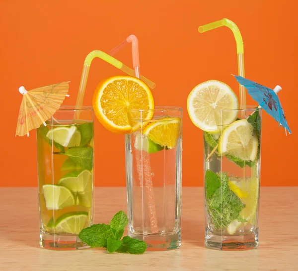 Cocktail with a straw and an umbrella, drink with an orange slice, tea with a lemon, on a table — Stock Photo, Image