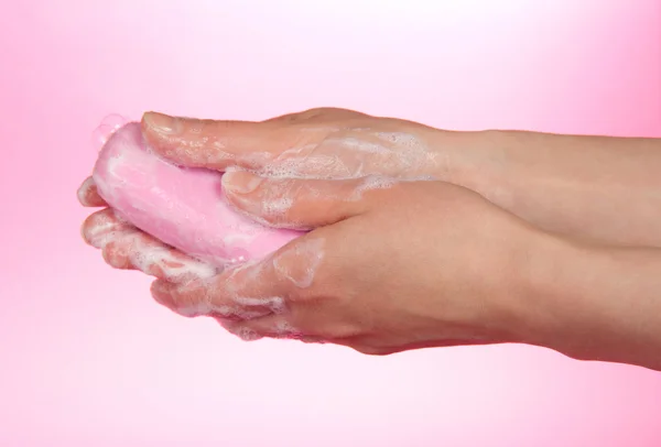 Pezzo di sapone fragrante nelle mani femminili su uno sfondo rosa — Foto Stock