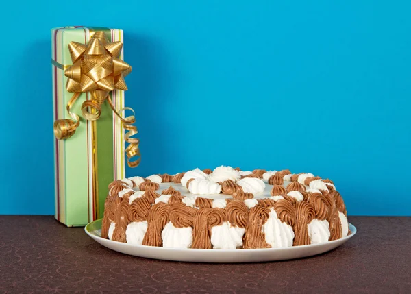 Torta su un piatto e una scatola regalo su un panno marrone sul blu — Foto Stock