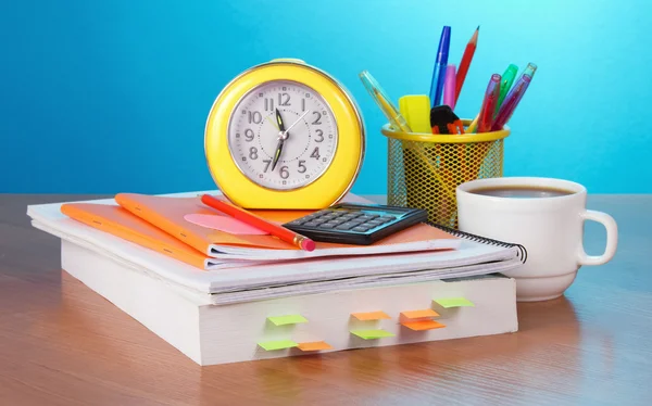 Het boek, alarm klok de calculator, vulpotloden en behandelt in een steun, een kopje koffie op een tafel — Stockfoto