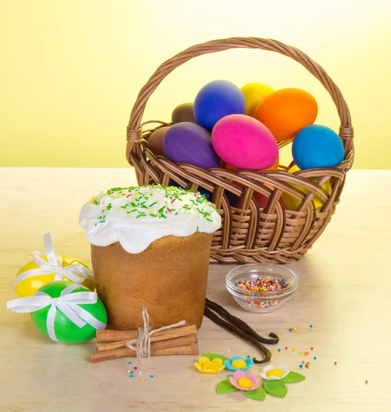 Easter cake, basket with eggs, vanilla and cinnamon, on a table on a yellow background — Stock Photo, Image