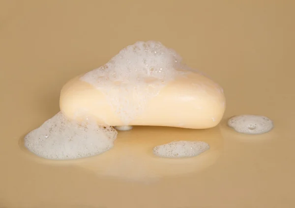 Natte zeep met schuim op een beige achtergrond — Stockfoto