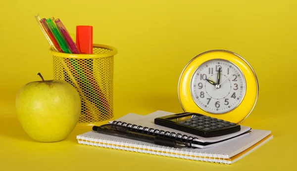 El libro de ejercicios, la calculadora, las manos en el soporte el reloj despertador y la manzana — Foto de Stock