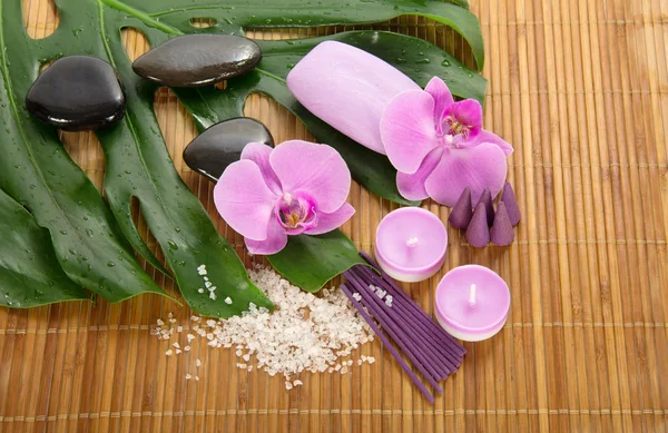 Monstera hoja, orquídea y conjunto para Spa en un paño de bambú — Foto de Stock