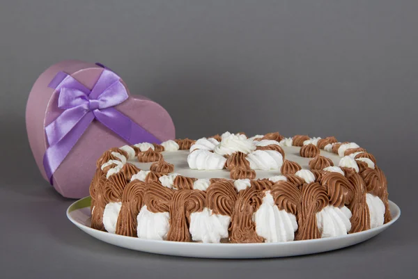 Pie on a dish and a gift heart on a gray background — Stock Photo, Image