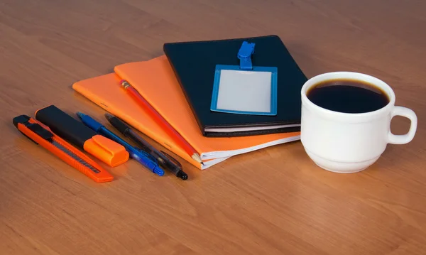 Una serie di accessori alla lettera distintivo vuoto e una tazza di caffè su un tavolo — Foto Stock