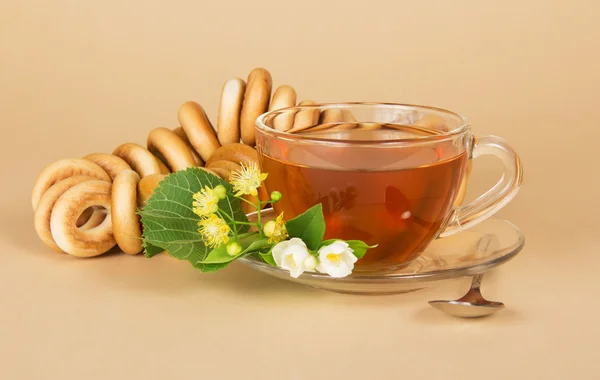 Kopp te, bagels, linden och jasmin blommor, på beige bakgrund — Stockfoto