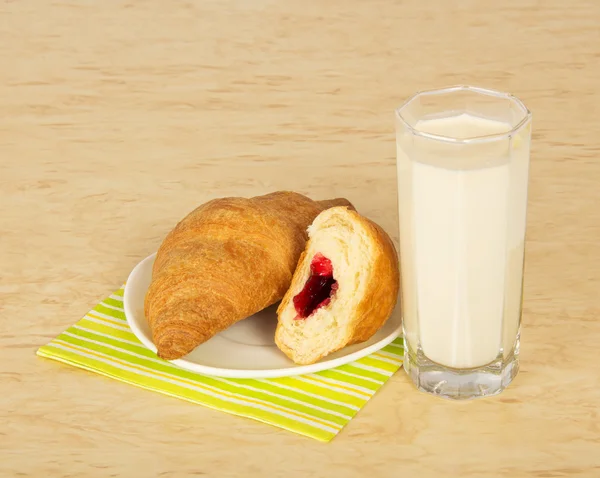 Croissants op een gestreepte servet en een glas melk, op een tafel — Stockfoto
